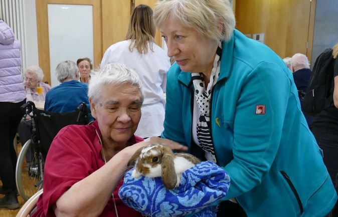 Seniorin streichelt Kaninchen bei Osterbesuch im St Elisabeth
