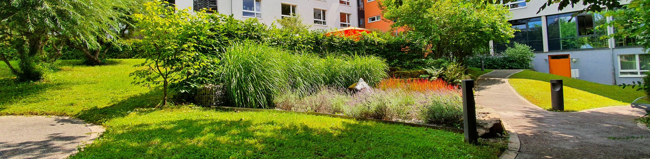 Mehrgeschossiges Wohngebäude mit grüner Innenhofanlage und geschwungener Fußweg