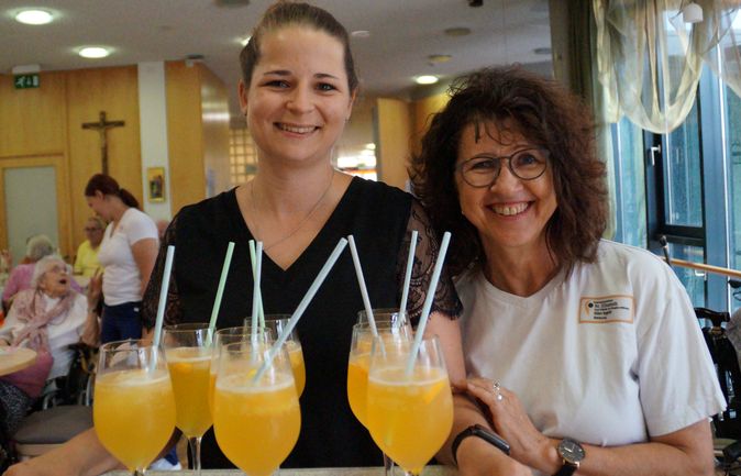 Zwei Mitarbeiterinnen in St. Elisabeth mit Tablett voller Orangencocktails