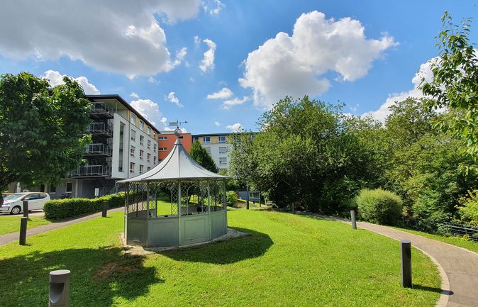 Spitzdach-Pavillon auf grünem Rasen vor Wohngebäuden und Bäumen